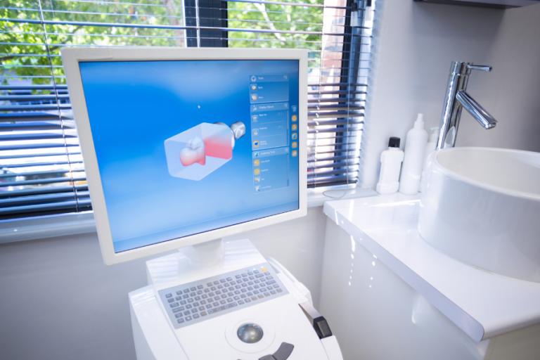 A dental CAD/CAM system displaying a 3D model of a tooth on a computer screen in a high-tech dental office.