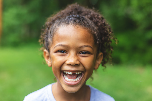 Smiling and making faces series 6 year old African American Chinese Ethnicity girl posing for portrait in lush green outdoor back yard setting (Shot with Canon 5DS 50.6mp photos professionally retouched - Lightroom / Photoshop - original size 5792 x 8688 downsampled as needed for clarity and select focus used for dramatic effect)